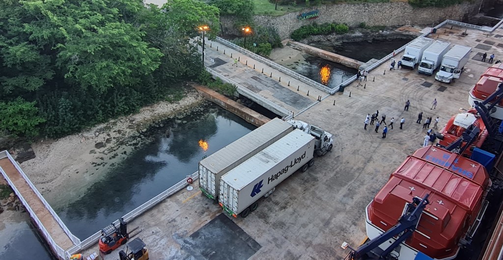 La Romana - Lkw stehen mit laufenden Motoren am Schiff, werden entladen und es lrmt und scheppert.